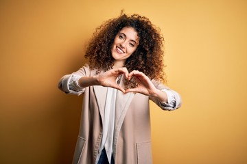 Young beautiful brunette woman with curly hair and piercing wearing casual t-shirt and diadem smiling in love doing heart symbol shape with hands. Romantic concept.