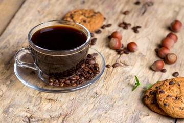 Black coffee in a glass cup with coffee beans. near cookies and hazelnuts