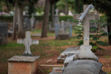Christian cemetery. Stone tomb with crucifix in the foreground with trees behind.