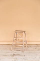 The working space of the photo studio with a beige paper background and chair.