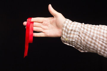 Red ribbon on the hand of an adult person