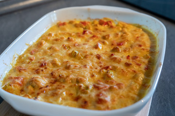Cheese curry chicken baked in a ceramic form on background wooden table