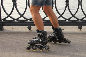 A man in shorts without safety equipment kneepads skating with rollerblades on a asphalt road alley...