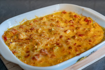 Cheese curry chicken baked in a ceramic form on background wooden table