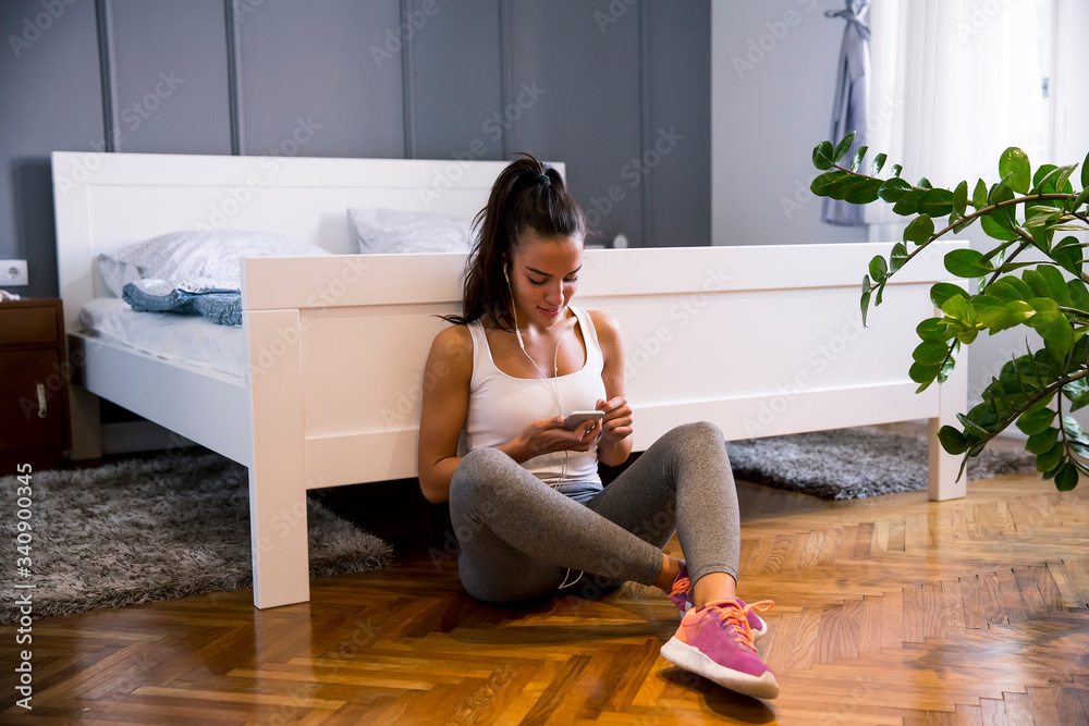 Wall mural young fit woman choosing right musing for the exercises at home