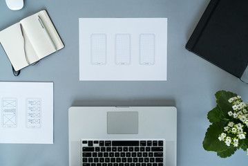 Web designer at work. Graphic designer. Mobile application design. Designer desk. UX, UI design. Thumbnails of a mobile application sketches. Laptop, sketchbook, pencil on the table.
