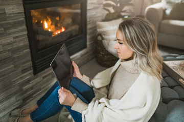 Young woman working from home on her tablet in cozy living room