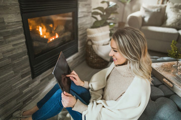 Young woman working from home on her tablet in cozy living room