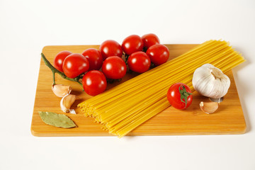 Tomatoes, garlic, pepper and spaghetti on the Board, white background