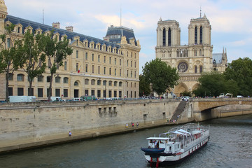 Fototapeta premium Paris, France - August 26, 2018: Tourists enjoy a boat trip on Seine river near Notre Dame cathedral.