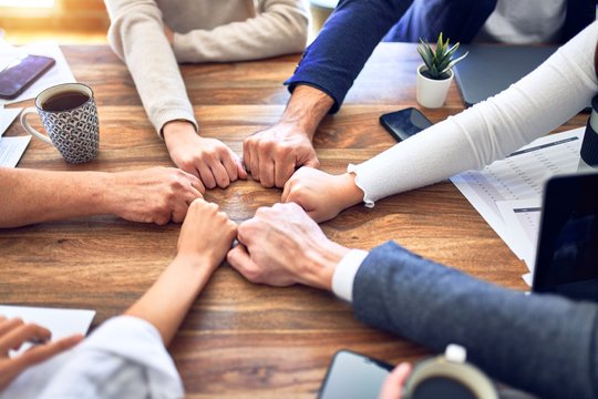 Group of business workers standing bumping fists at the office