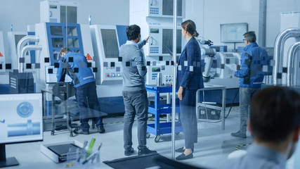 Modern Factory Office: Team of Industrial Engineers Working on Computers. In Factory Workshop: Professional Workers Use High-Tech Industrial CNC Machinery, Program Robot Arm, Have Meeting.