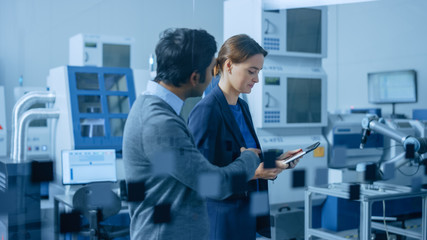 Modern Factory: Female Project Manager and Male Engineer Walk Through High Tech Development...