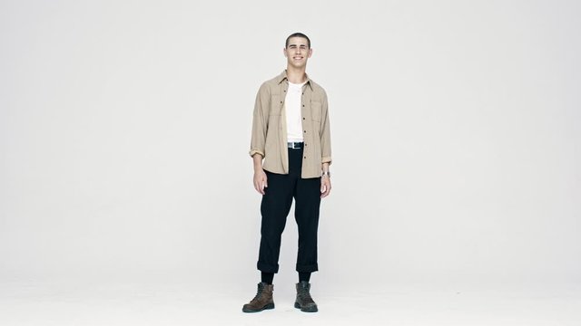 Full length of a happy young caucasian man looking at camera. Stylish man standing on white background and smiling.
