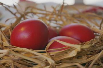 Bright red easter eggs in decorative straw nest. Concept easter table, symbol of holiday.