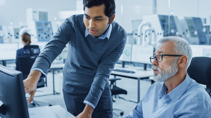 Modern Factory Office: Asian Project Manager Talks to Caucasian Senior Engineer who's Working on...