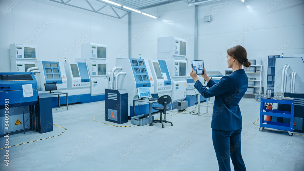 Aufkleber Modern Factory: Female Engineer Uses Digital Tablet Computer with Augmented Reality Software to Visualize Workshop for Room Mapping, Floor Layout. Facility with High-Tech CNC Machinery and Robot Arm