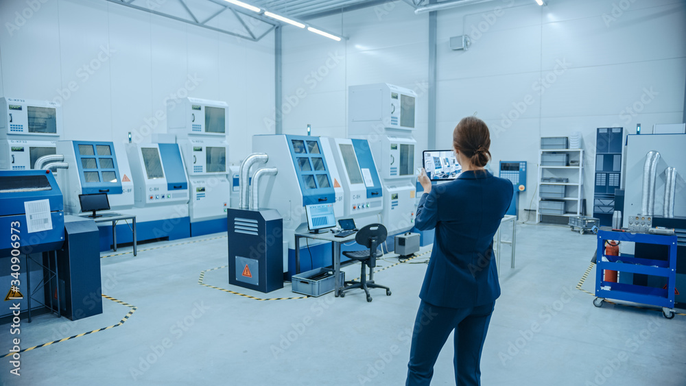 Poster Modern Factory: Female Engineer Uses Digital Tablet Computer with Augmented Reality Software to Visualize Workshop for Room Mapping, Floor Layout. Facility with High-Tech CNC Machinery and Robot Arm