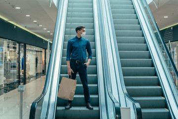 lone man in a protective mask standing on the escalator steps