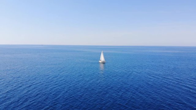 Aerial: bird's eye view of one sailing boat cruising in the open sea or ocean.