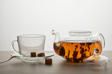 Cup and teapot of green tea with lemon and sugar isolated on white