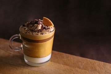 Dalgona coffee presented in a small glass, accompanied by cocoa