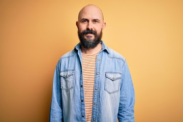 Obraz premium Handsome bald man with beard wearing casual denim jacket and striped t-shirt with a happy and cool smile on face. Lucky person.