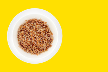 Deep white plate on a saucer with boiled buckwheat with copy space.