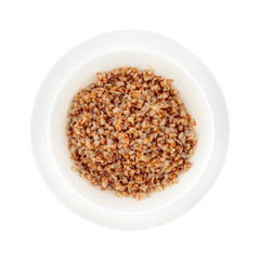 Deep white plate on a saucer with boiled buckwheat.
