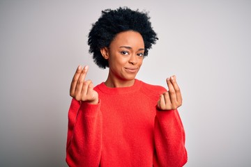 Young beautiful African American afro woman with curly hair wearing red casual sweater doing money gesture with hands, asking for salary payment, millionaire business