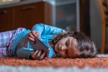 Cute little girl lying down looking at mobile