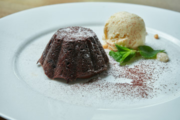 Chocolate fondant with a scoop of vanilla ice cream on a white plate on a wooden background. Mouth-watering dessert for breakfast