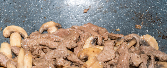 Homemade cooking veal and mushrooms in frying pan. Close-up macro photo of julian chopped meat....