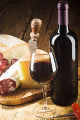 Red wine in vintage light with cheese and fruits.