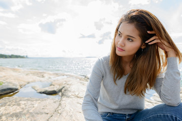 Fototapeta na wymiar Young beautiful Asian woman against scenic view of the lake