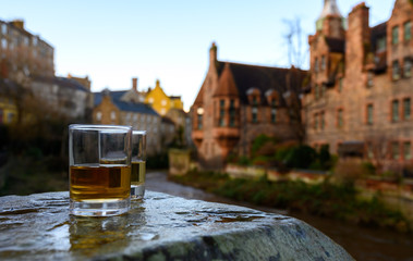 Scotch single malts or blended whisky spirits in glasses with old houses of Edinburgh on...