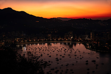 Panoramic night aerial view of Guanabara Bay and mountains of Rio de Janeiro and Christ the Redeemer in the background, coast of Brazil