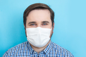 Man wearing medical mask on blue background, copyspace, copyplace, space for text. Coronavirus, illness, infection, quarantine, medical mask