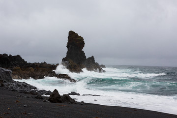 Black rock in a raging sea in the rain