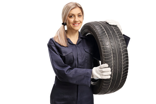 Young woman auto mechanic holding a car tire