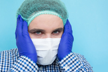 Tired doctor in medical mask touching his head isolated on blue background. Copyspace, copyplace, space for text. Coronavirus, illness, infection, quarantine, medical mask