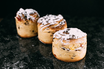 cruffins, The modern baking trend of the year is puffmuffin, a mix of croissants and cupcakes. On a black background sprinkled with powdered sugar