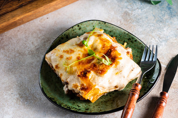 Piece of tasty hot lasagna with red wine. Small depth of field. Traditional italian lasagna. Portion. Italian food. Food on green plate. Bolognese sauce. Bechamel sauce. Still life of food.