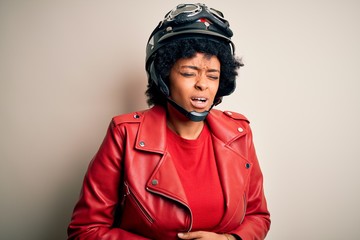 Young African American afro motorcyclist woman with curly hair wearing motorcycle helmet with hand on stomach because nausea, painful disease feeling unwell. Ache concept.