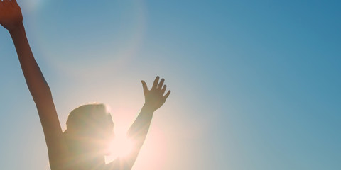 Silhouette of a girl with hands wide apart blue sky background