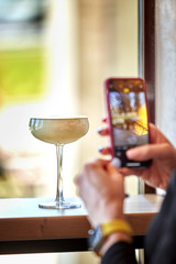 The concept of a blogger photographing alcoholic beverages in a transparent glass. A glass on a thin leg. Blogging about drinks.