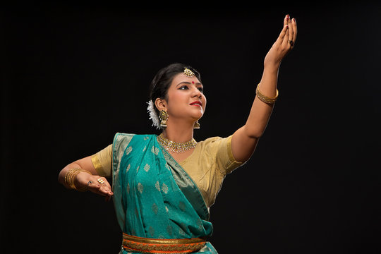 Beautiful kathak dancer performing gracefully over a dark background. 
