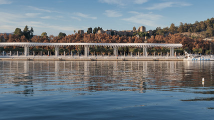 Panorama view of the Malaga Alcazaba Fortress and promenade in Spain from The Port of Malaga Quay 1 on a sunny day.