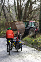 Cyclists riding on country lanes following a tractor in the background