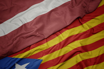 waving colorful flag of catalonia and national flag of latvia.
